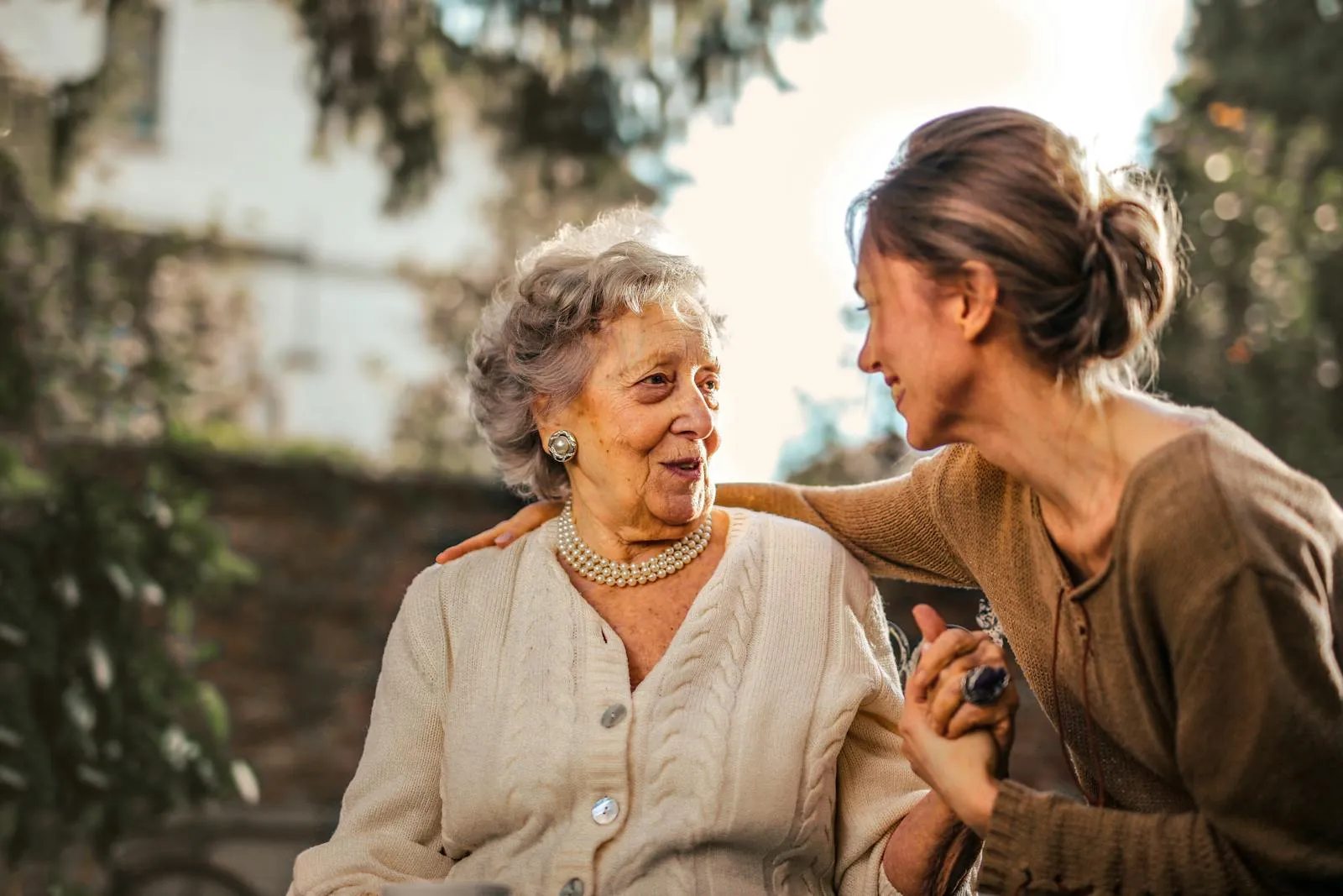 A caregiver and a smiling senior sharing a moment outdoors